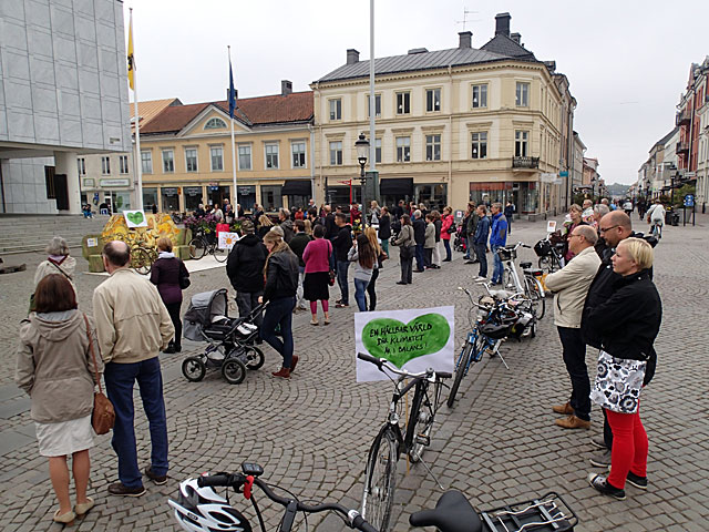 Bilden visar en lång rad cyklar parkerade på gågatan och åhörare på båda sidor om cyklarna. 