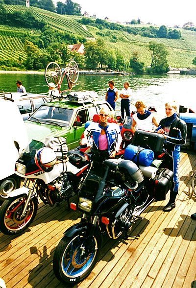 Bilden visar alla resenärer utom Hjalmar, som står vid motorcyklarna på en färja.
