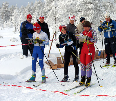 Bilden visar några deltagare vid startlinjen, som kollar på sina kartor.