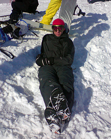 Bilden visar Daniel, som sitter på snön och solar med brädan som ryggstöd. 