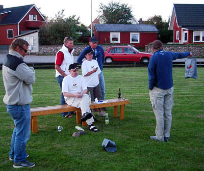 Bilden visar knoX-besättningen på en gräsmatta. Två funktionärer kontrollerar hur ett tävlingsmoment utförs.