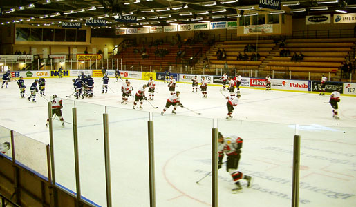 Bilden visar Gärdehovs hockeyhall inifrån, med två lag som värmer upp på isen.