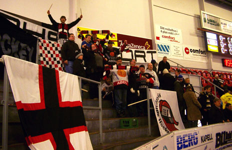 Bilden visar gänget, och några till, på Björklövens ståplatsläktare. Många flaggor och banderoller är upphängda på räcken. Hjalmar står högst upp med en trumma och armarna uppsträckta med trumpinnar.